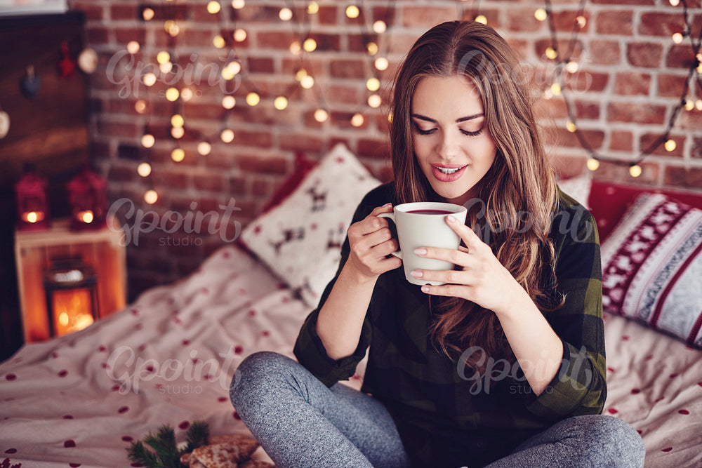 Lovely woman drinking coffee in her bedroom