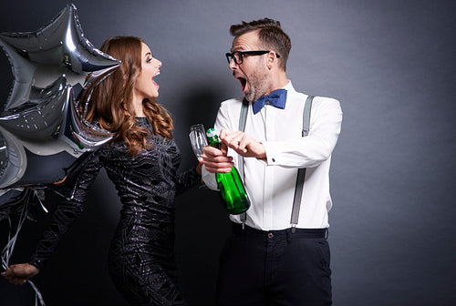 Couple uncorking bottle of champagne
