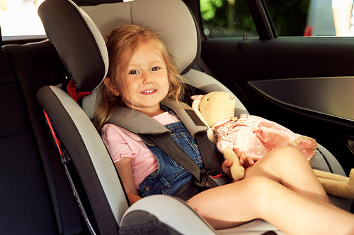 Portrait of little girl sitting in the baby car seat