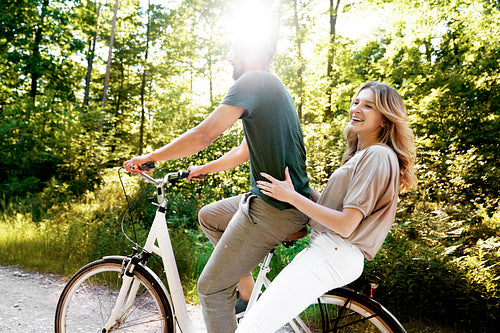 Couple on a bike in the woods on a sunny day