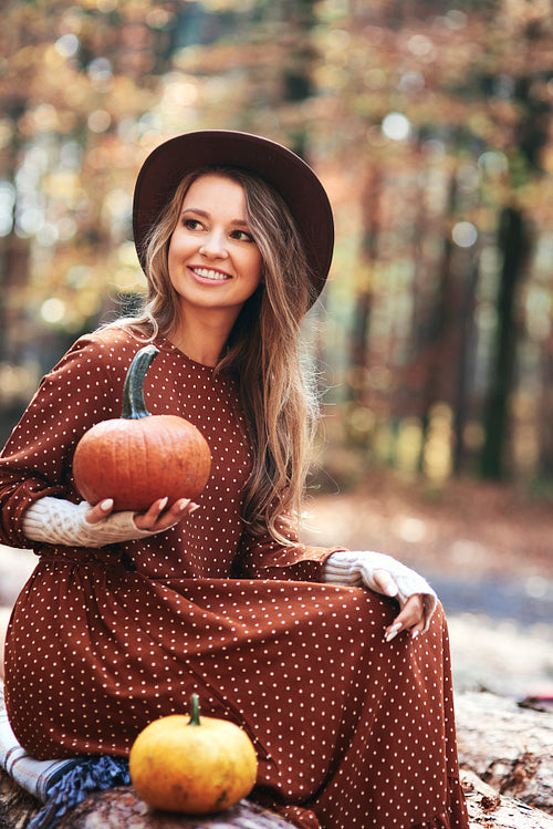 Beautiful woman holding pumpkins in autumn woods