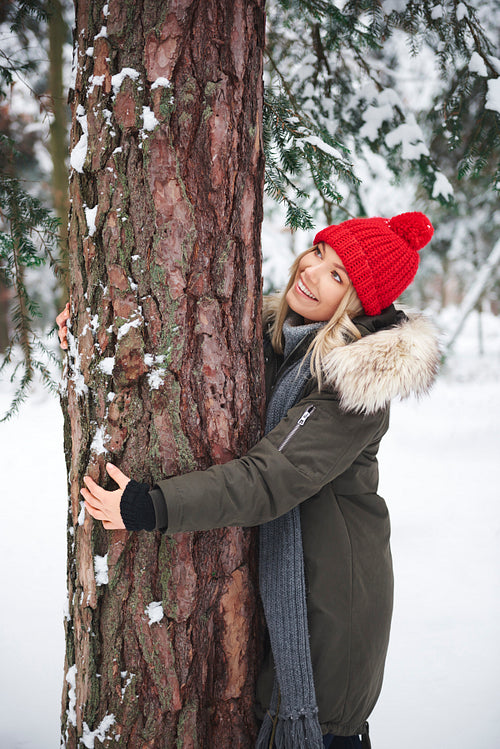 Young women embracing tree in winter forest