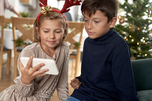 Two caucasian children using mobile phone during Christmas time