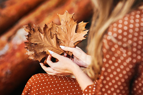 Close up of woman with a bunch of autumnal leaves