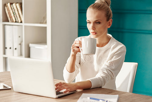 Businesswoman with coffee using laptop