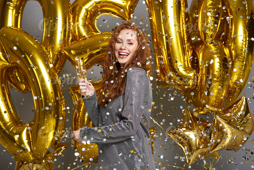 Woman drinking champagne under shower of confetti