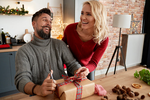 Couple have fun while packing Christmas present