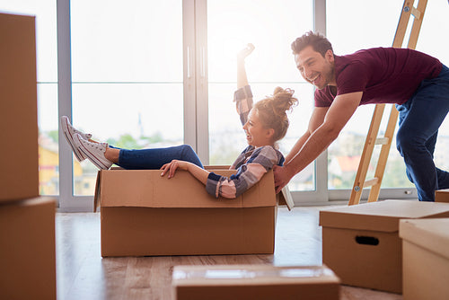 Playful couple having fun with boxes during move house