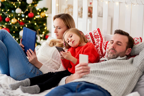 Bored family using mobile phone in bed at Christmas