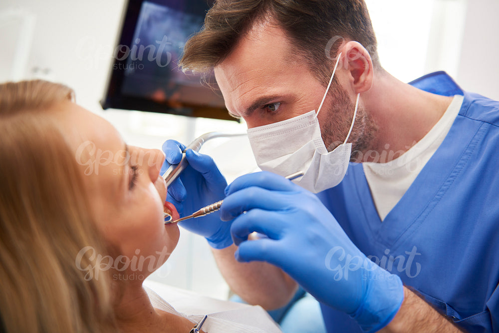 Focused stomatologist treating woman for dental cavity