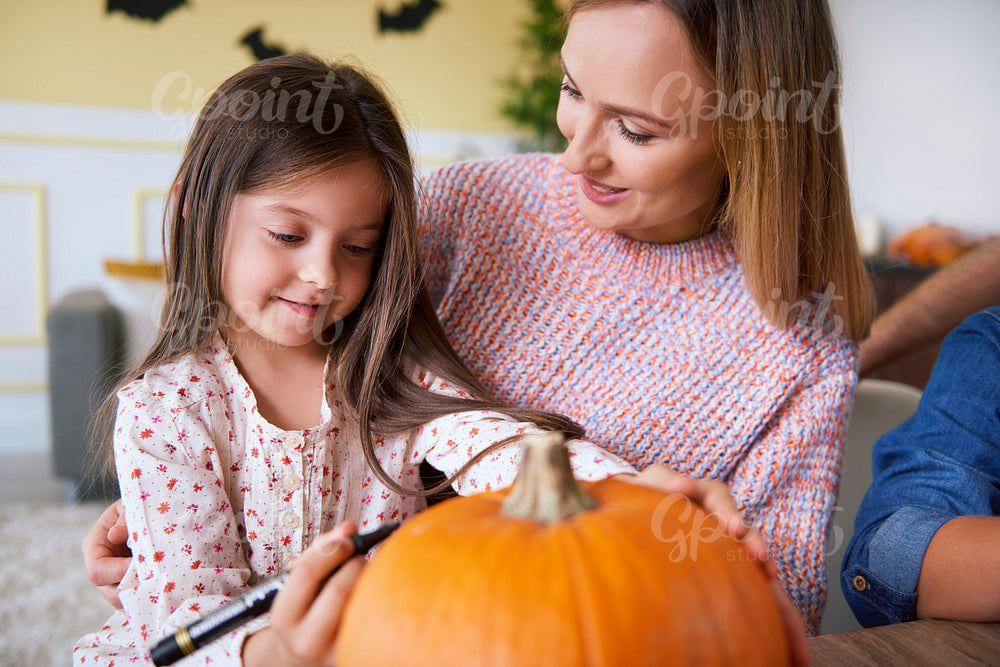 Mother and child drawing on pumpkin