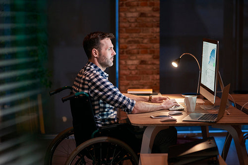 Side view of disabled businessman working in office