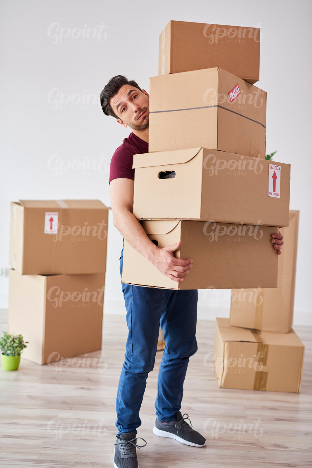 Portrait of man carrying stack of heavy cardboard boxes