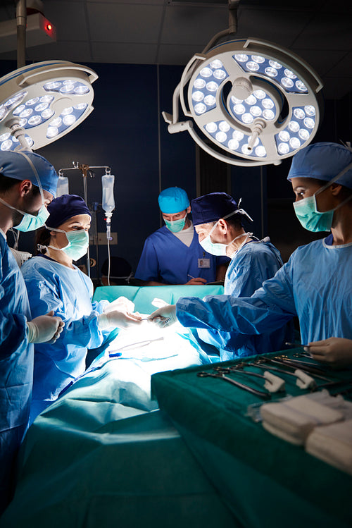 Team of surgeons during serious operation in darkness