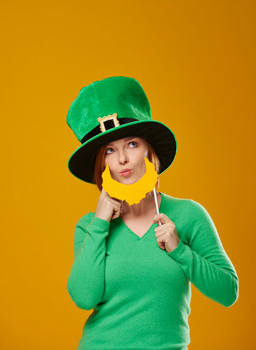 Playful woman in leprechaun costume looking at copy space