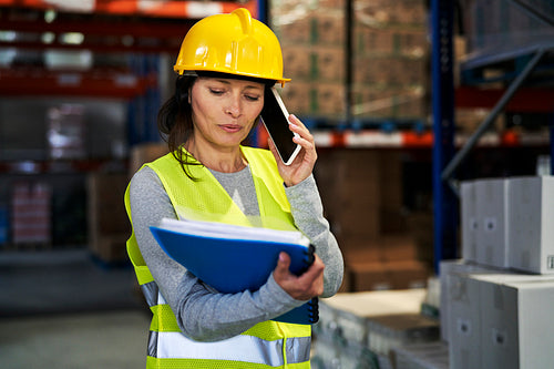 Adult caucasian woman talking by mobile phone in warehouse