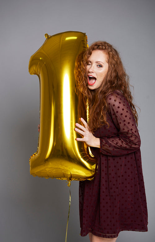 Young woman with golden balloon celebrating first birthday her company