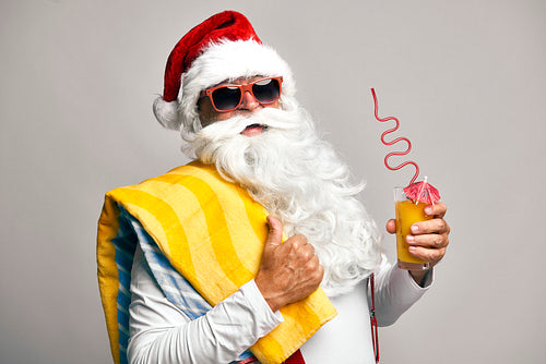 Caucasian Santa Claus with drink and sunglasses on grey background