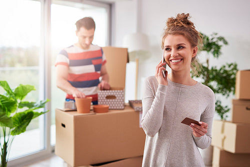 Smiling woman talking by mobile phone during moving out