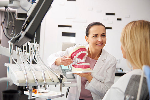 Smiling stomatologist and woman holding a conversation in dentist's clinic