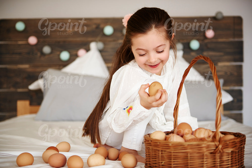 Cheerful girl watching the eggs in bed