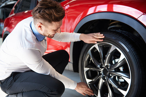 Salesman checking the shiny rims in new car