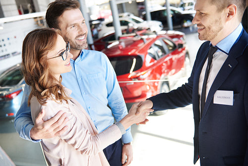 Mid adult couple making a great deal with salesman