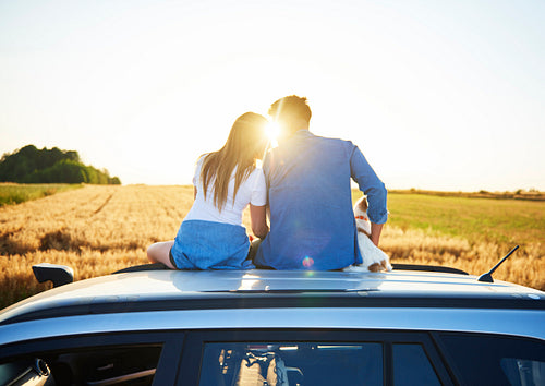 Rear view of loving couple embracing and sitting on car