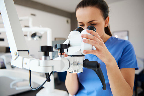 Close up of female dentist looking through dental microscope