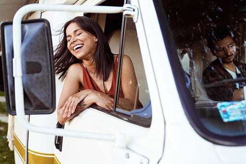 Cheerful mixed race woman  sticking out of camper's window
