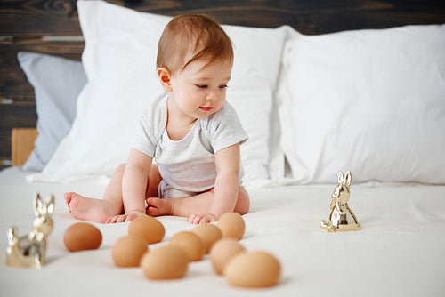 Baby playing with egg on the bed