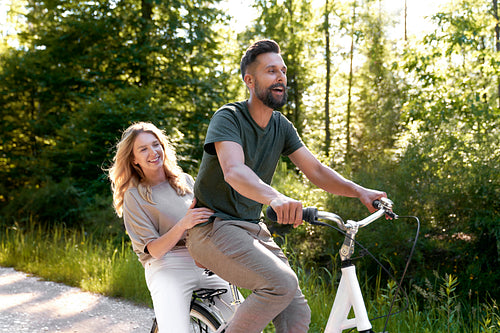 Playful couple having fun on a bike in the woods