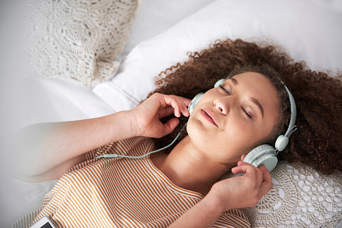 Teenage girl listening to music and lying on the bed