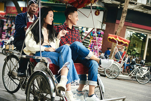 Wide shot of couple traveling by Vietnamese  pedicab