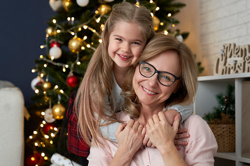 Portrait of happy grandmother and granddaughter embracing in Christmas time