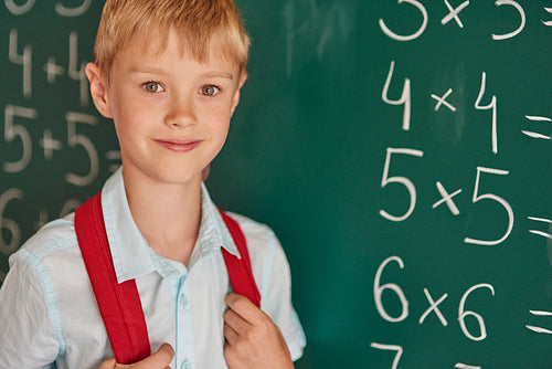 Boy standing next to the blackboard