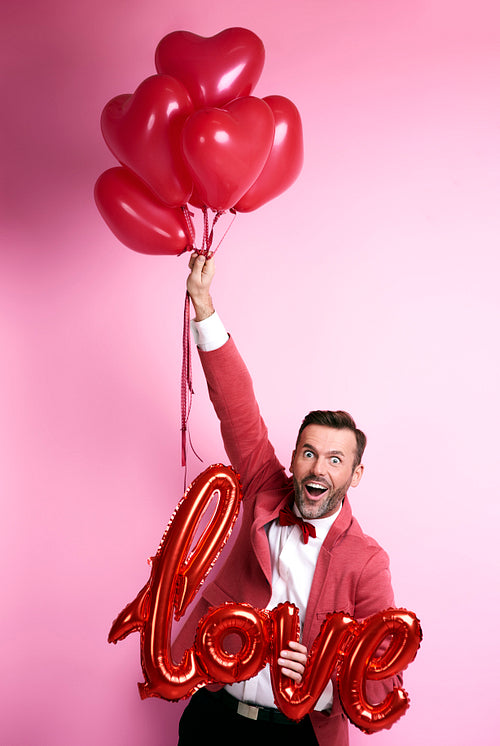 Funny man holding bunch of balloons heart shape