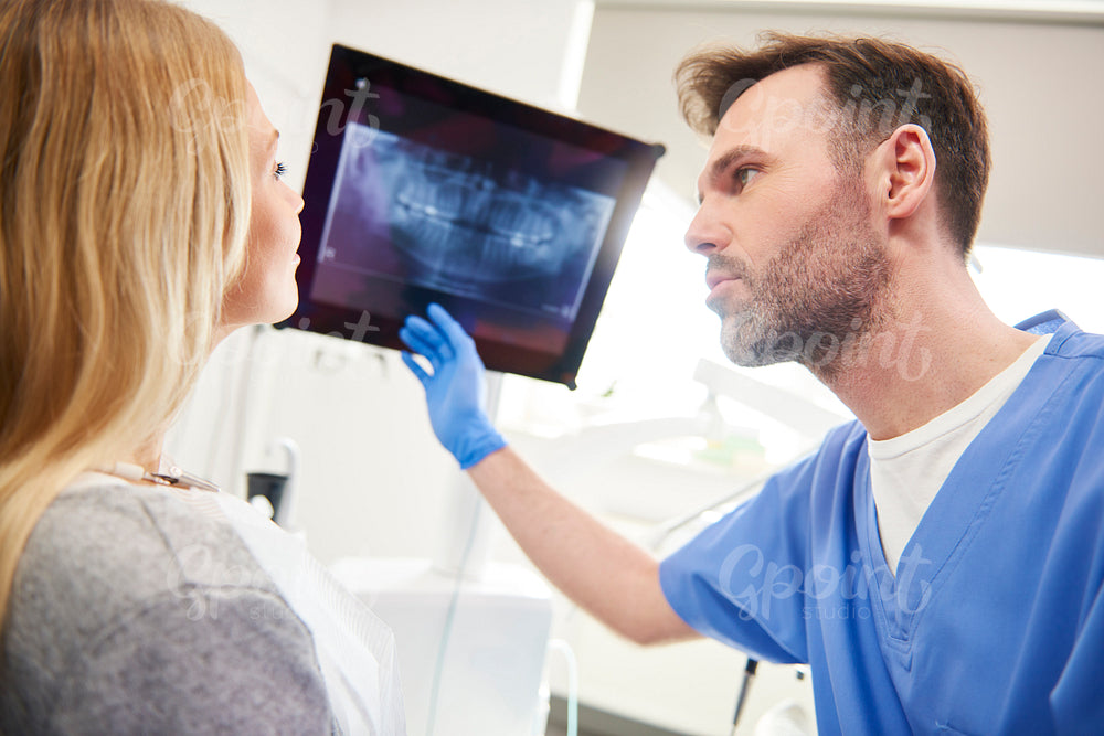 Dentist pointing at x-ray and examining patient the woman's teeth