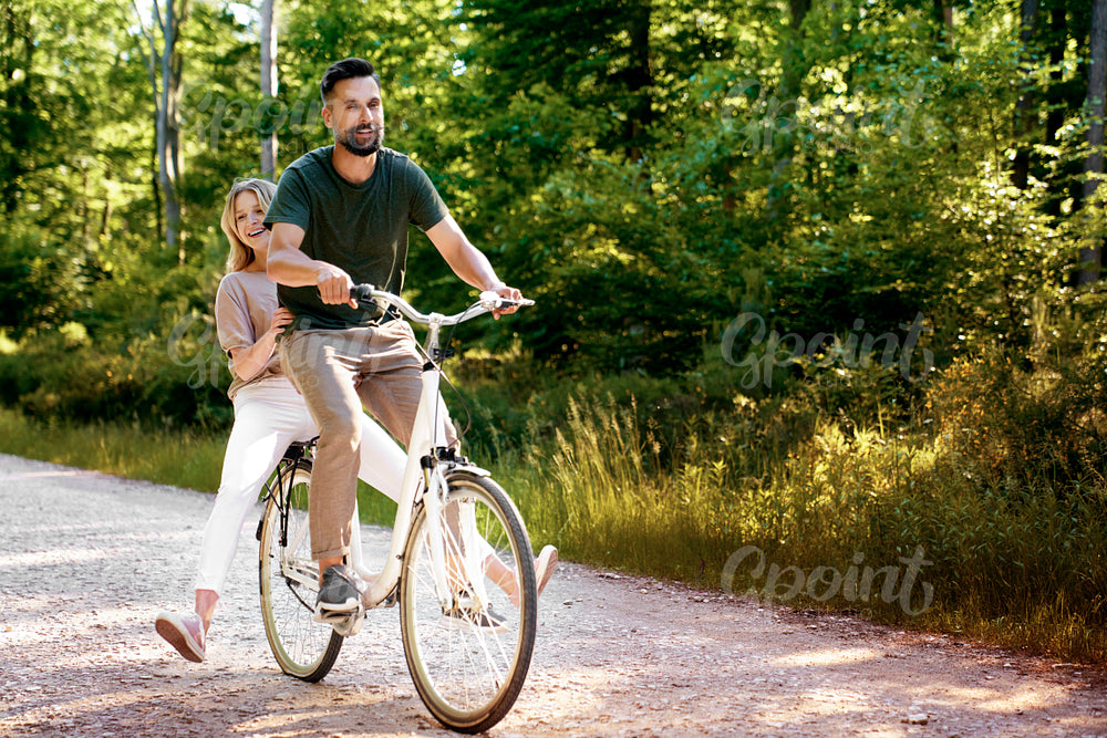 Playful couple having fun on a bike in the forest