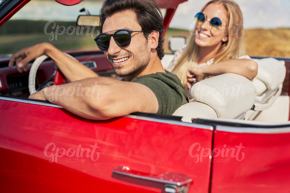Portrait of happy couple sitting in red car