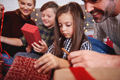 Close up of family opening christmas presents in bed