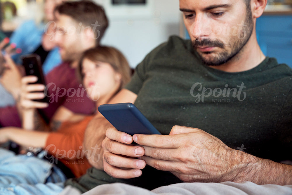 Man focused on smart phone at party