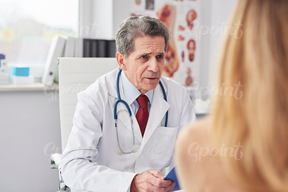 Senior doctor talking with woman in doctor’s office