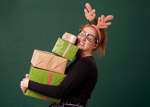 Funny woman carrying stack of heavy christmas gifts