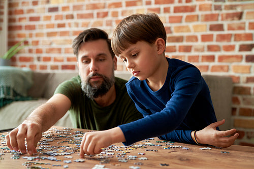 Father and child solving jigsaw puzzle together