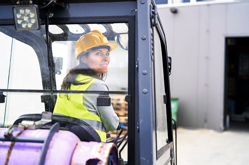 Back view of adult caucasian woman driving a forklift