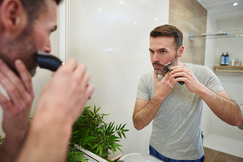 Mature man with electric razor shaving in bathroom