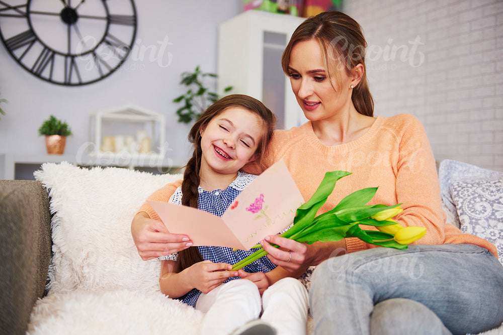 Young mom receiving greeting card and flower on Mother's Day