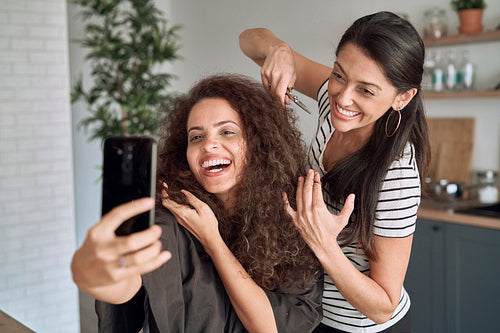 Happy women taking funny selfie during trimming their hair