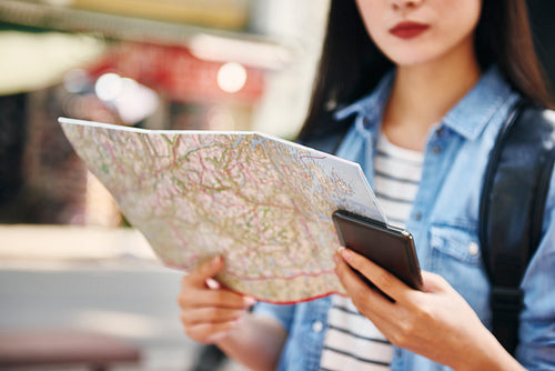 Close up of tourist with map and mobile phone